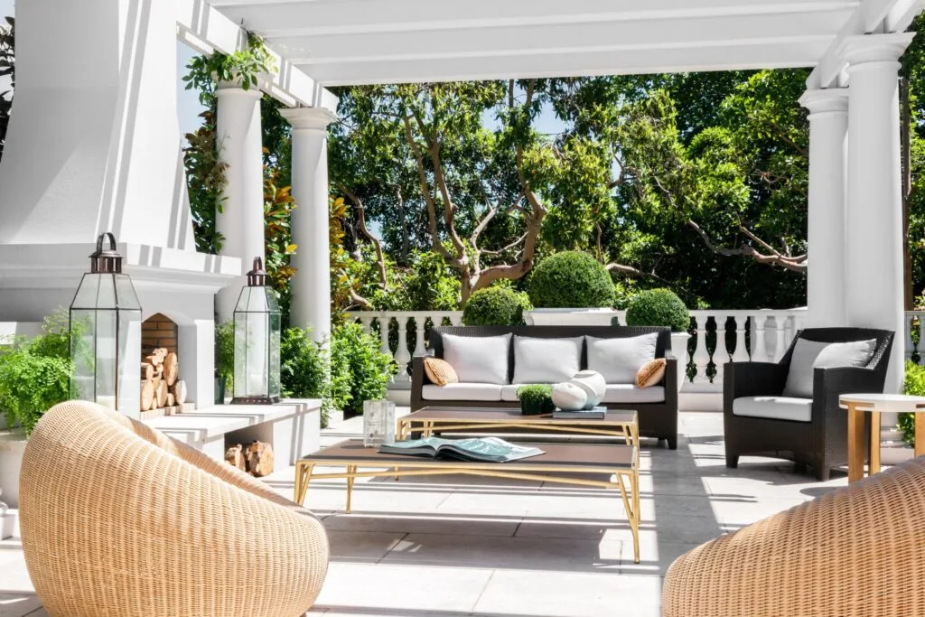 An all-white outdoor seating area with curved rattan chairs