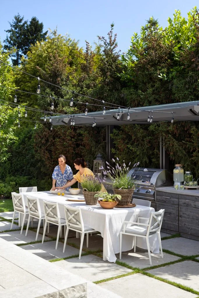 Designers Kelly and Chelsea setting the table by the outdoor kitchen.