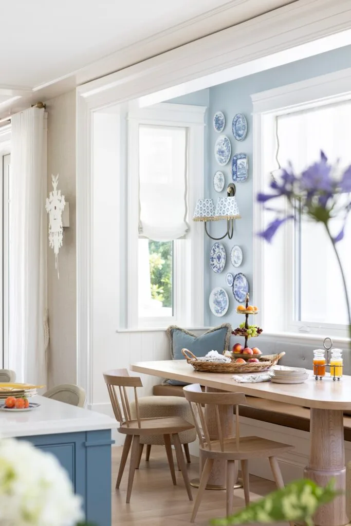 A timber breakfast nook below a wall gallery of decorative plates.