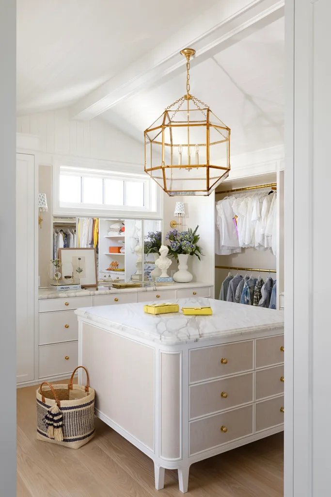 A white dressing room with a gold geometric pendant and marble drawers.