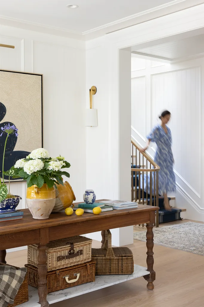 A timber table in the foyer decorated with cane suitcases, flowers and books.