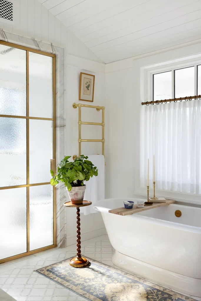 The main ensuite with a freestanding bath, gold towel rack and gold glass doors.