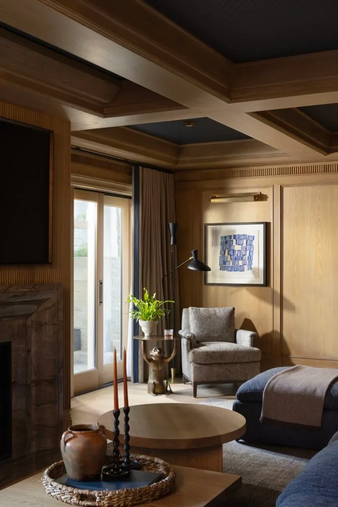 A timber sitting room with ceiling beams, decorative wall panels and a blue sofa.