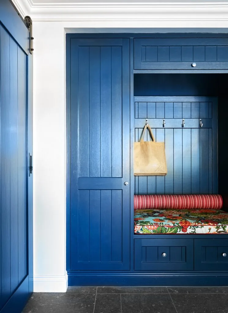 A mudroom with navy joinery and a floral bench.