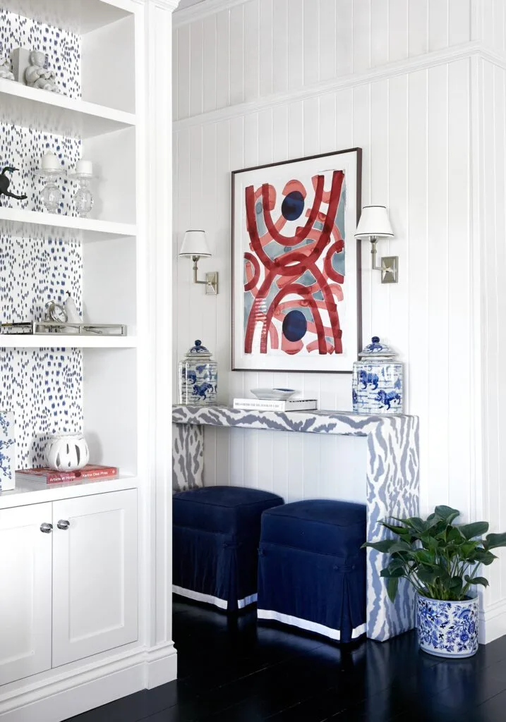 An entrance hall with white wall panels, a blue console and open shelves.