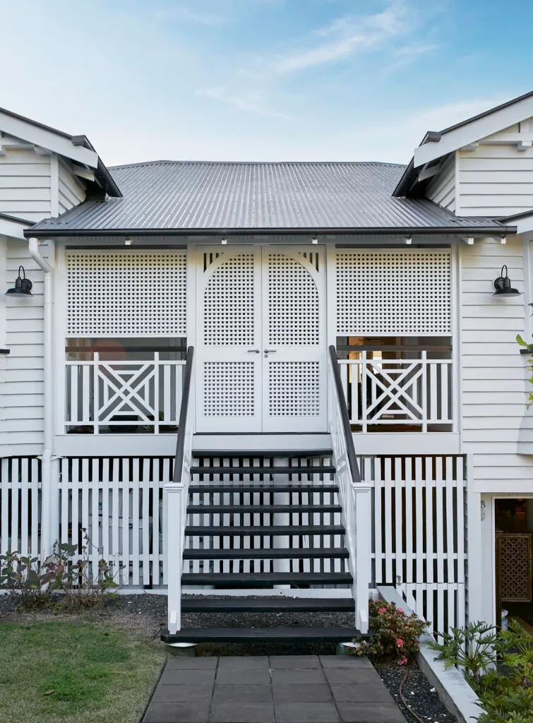 A classic Queenslander house with a white fretwork exterior.