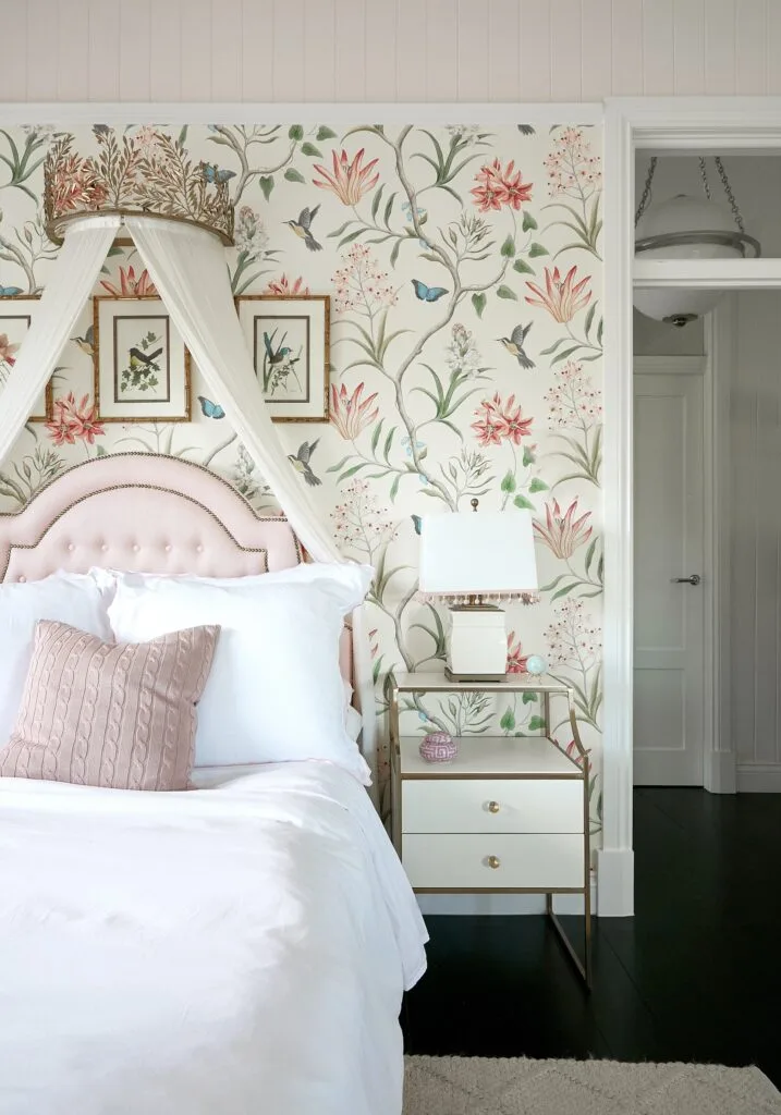 A children's bedroom with floral wallpaper and a custom draping curtain.