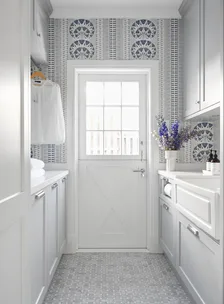 A laundry room with blue patterned wallpaper and a farm-style door.