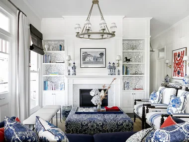 An American-style living area with patterned blue sofas, a fireplace and white wall panelling.