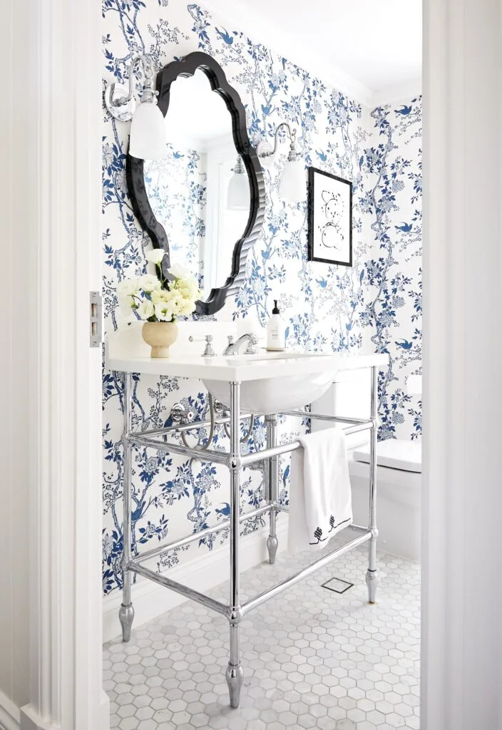 A classic-style powder room with a pedestal basin and blue floral wallpaper.