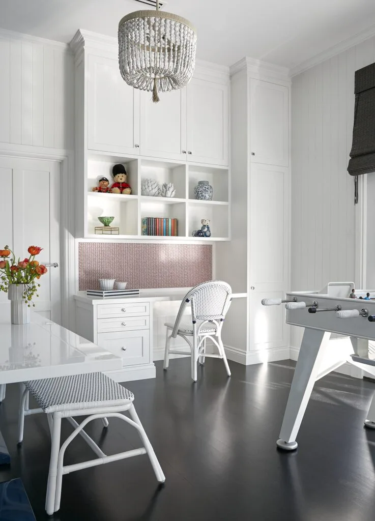 A white rumpus room with a table, open shelves and a foosball table.