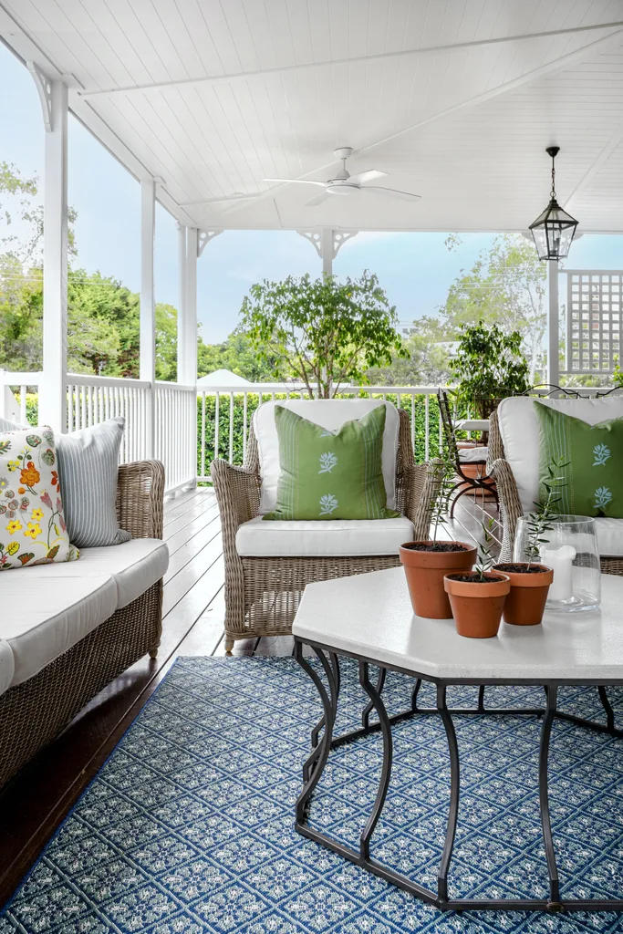 An outdoor deck area with rattan chairs and a blue rug.