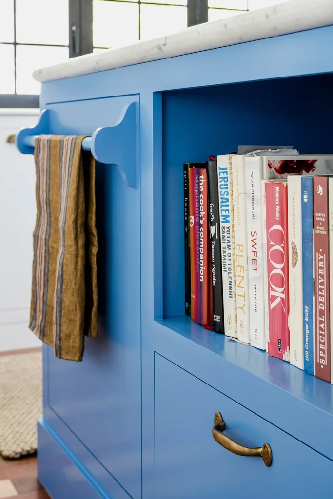 Blue kitchen cabinets with open shelves holding books.