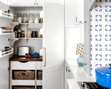 A white open pantry with rattan baskets and shelving.