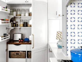 A white open pantry with rattan baskets and shelving.