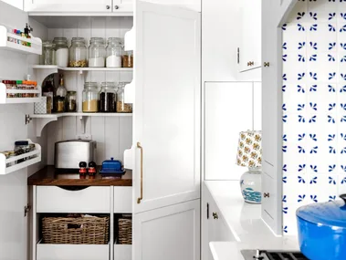 A white open pantry with rattan baskets and shelving.
