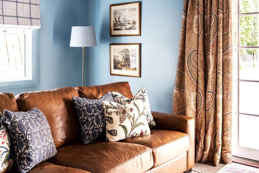 A media room with a leather sofa and paisley brown curtains.