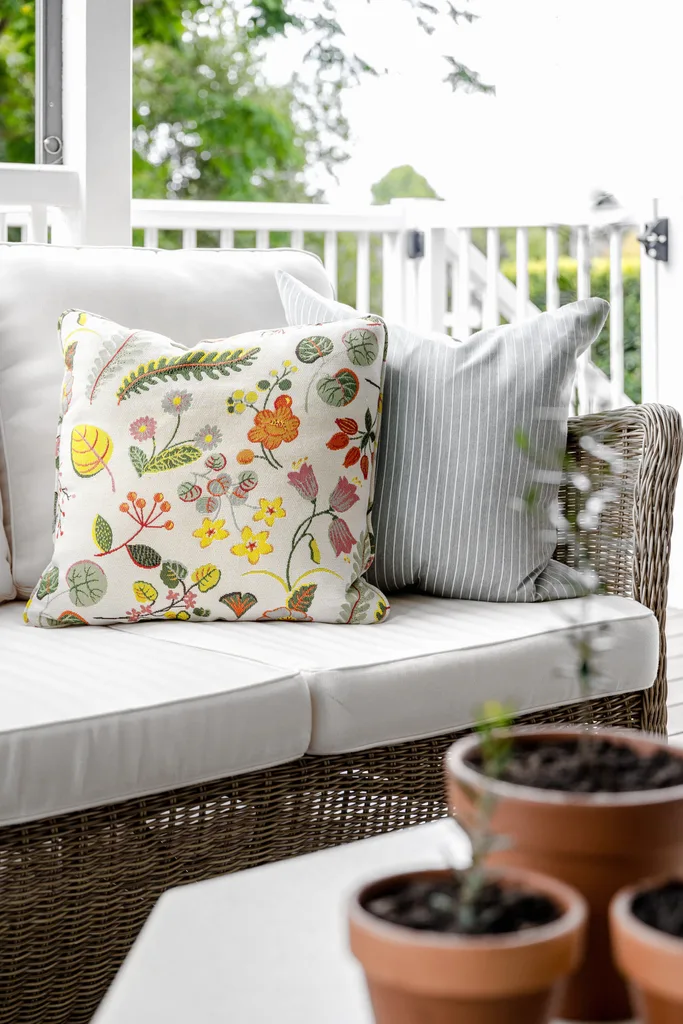 Floral and striped cushions on an outdoor rattan sofa.