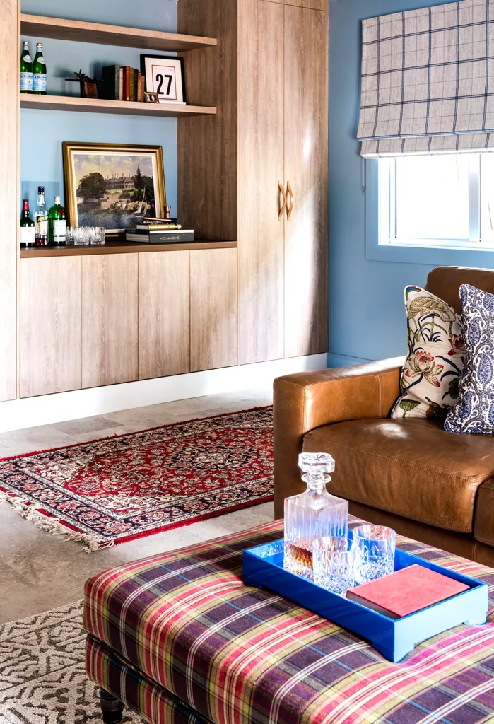 A bar area and cabinet beside a vintage rug and leather sofa.