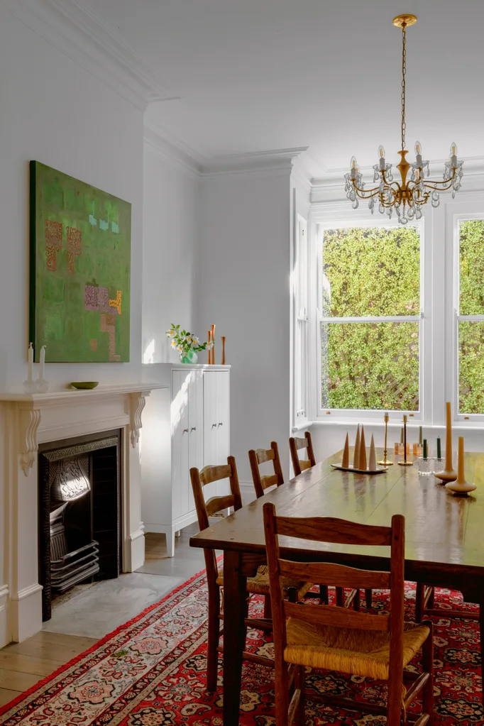 A classic dining room with a timber table, chandelier and abstract green wall art.