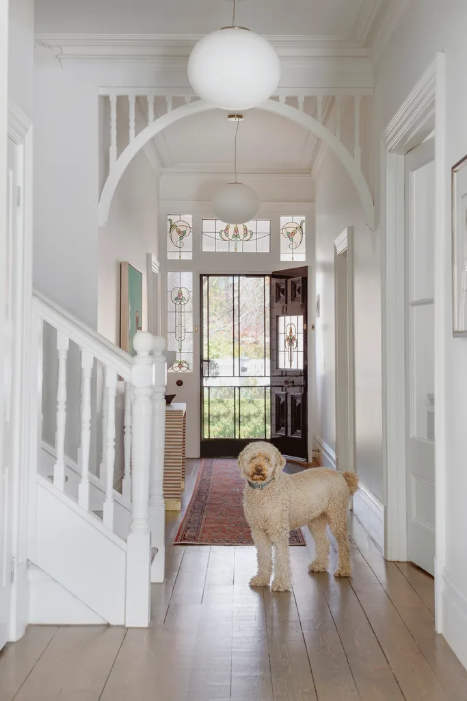 A heritage style hallway with fretwork and a fluffy dog standing by a staircase.