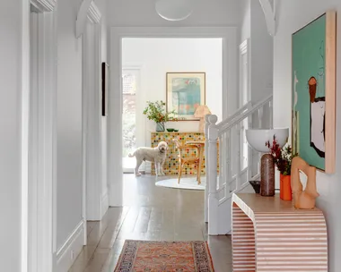 A heritage style hallway with decorative fretwork and a red hallway runner.