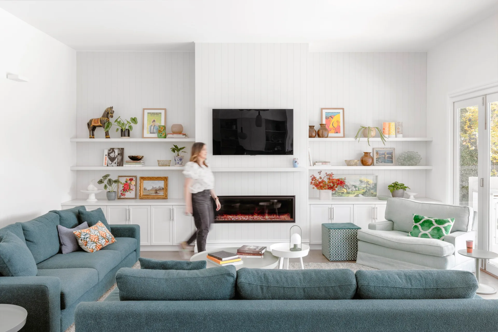 A contemporary living area with blue sofas, an inset fireplace and open shelving.