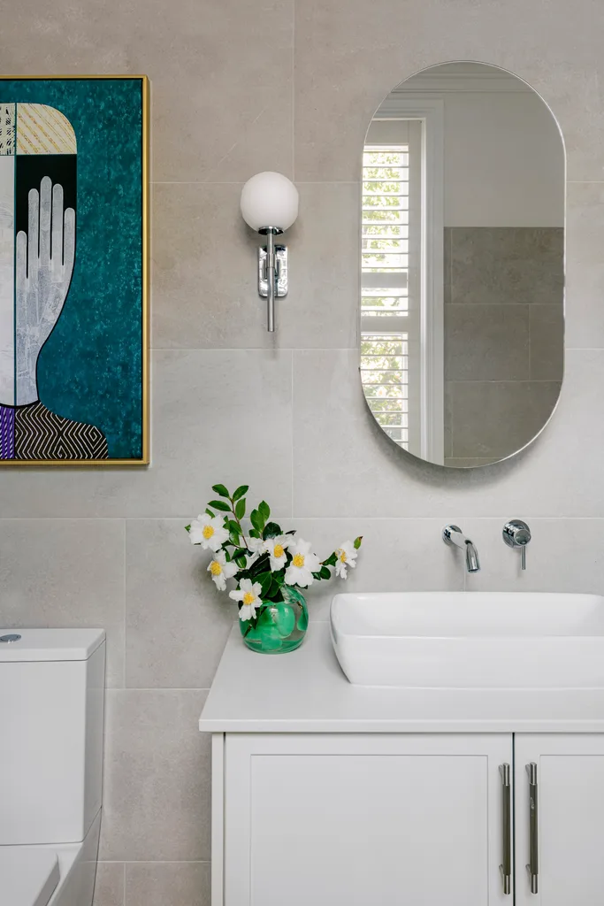 An ensuite with neutral tiles, a white vanity and a blue abstract artwork.