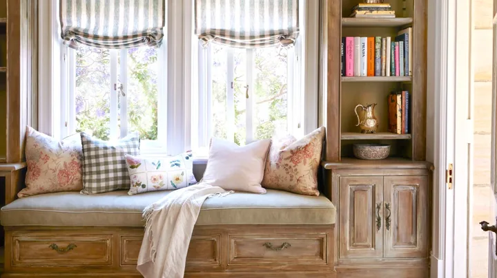 A window seat below a chandelier with decorative ceiling mouldings.