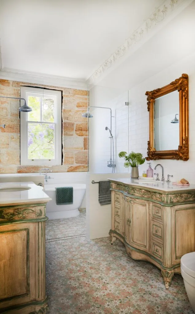 A French vintage style family bathroom with a double shower and sandstone wall.