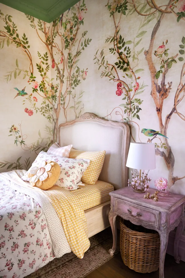 A children's bedroom with tree wallpaper and French style furniture.
