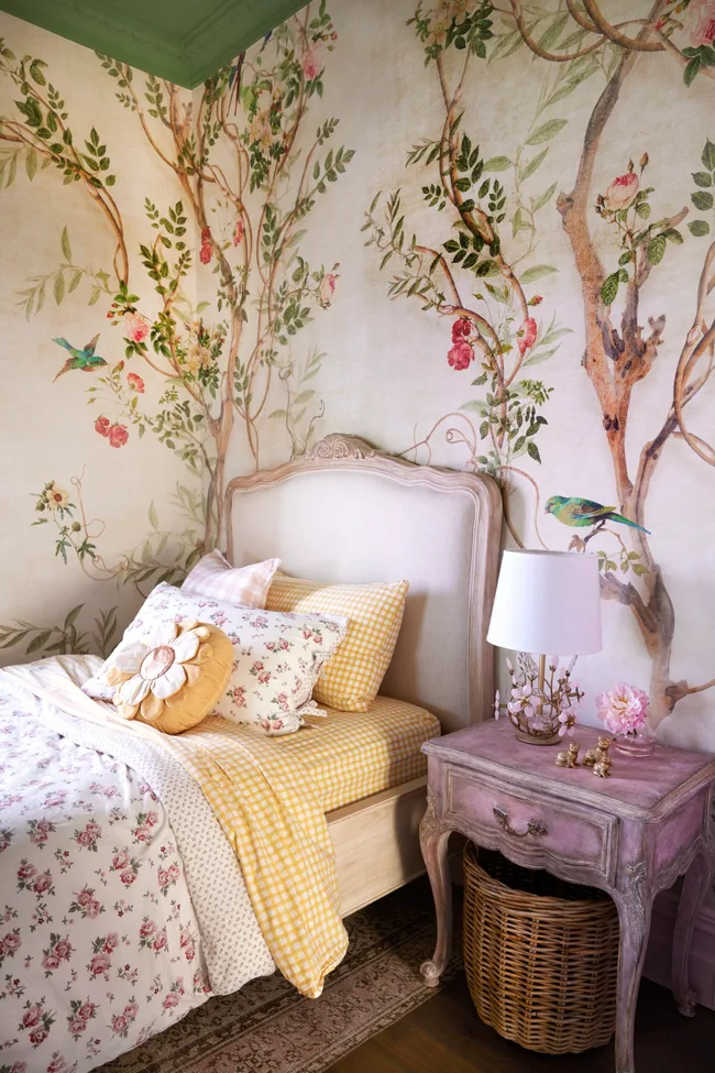 A children's bedroom with tree wallpaper and French style furniture.