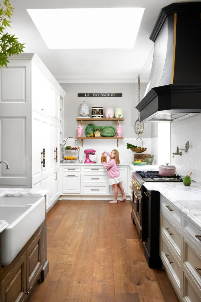 The kitchen area with shaker cabinets, a black stove top and skylight.