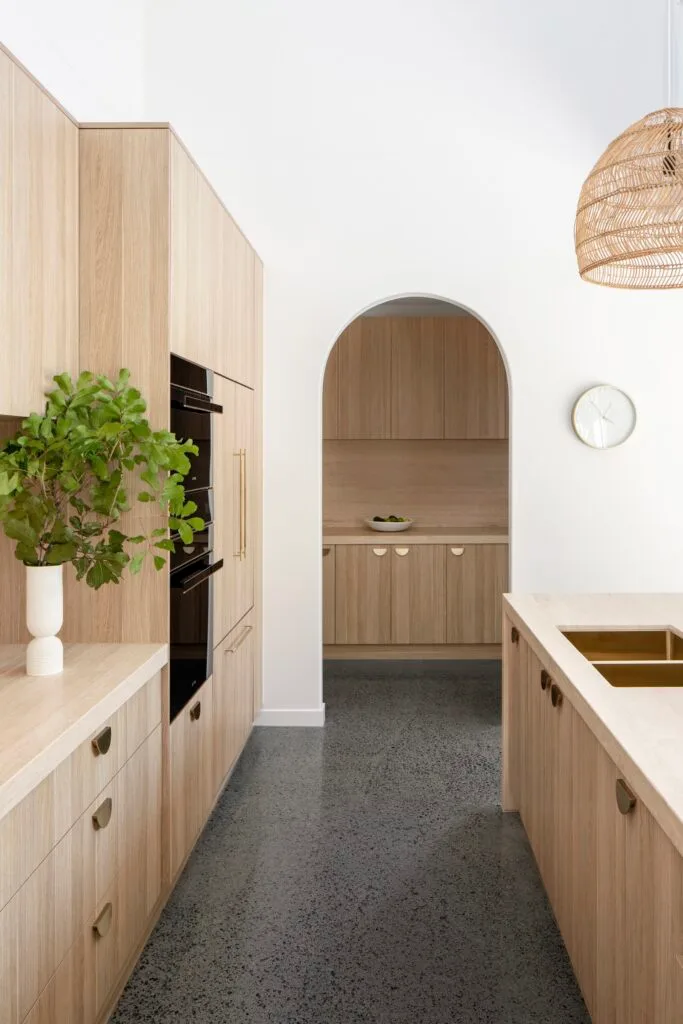 A modern kitchen with timber cupboards and slim gold handles.