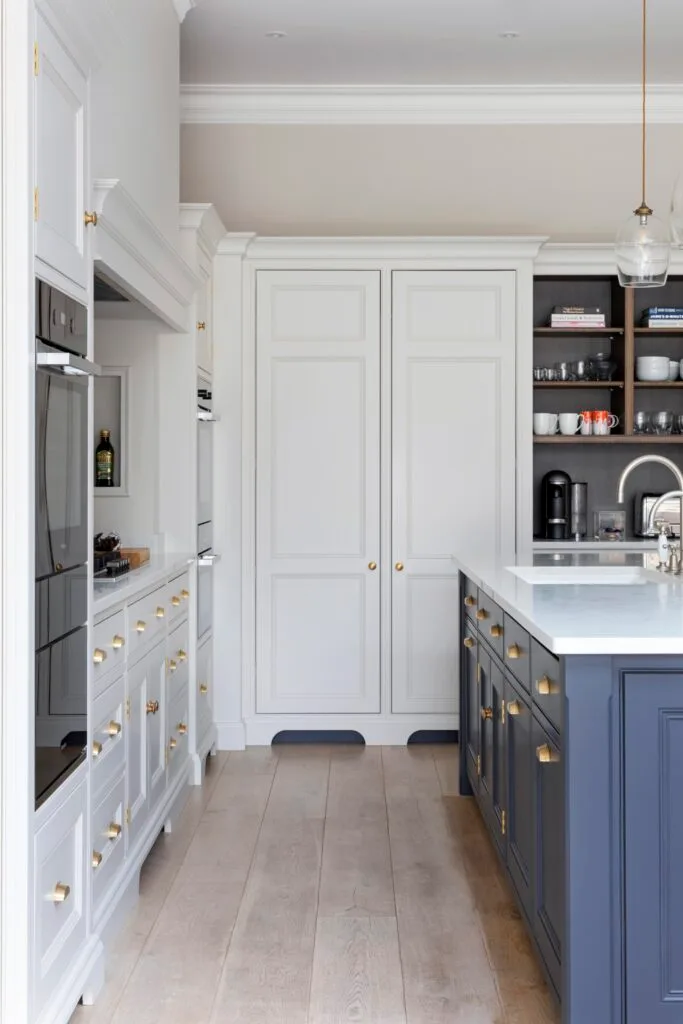 A white and blue kitchen with classic shaker cupboards and gold handles.