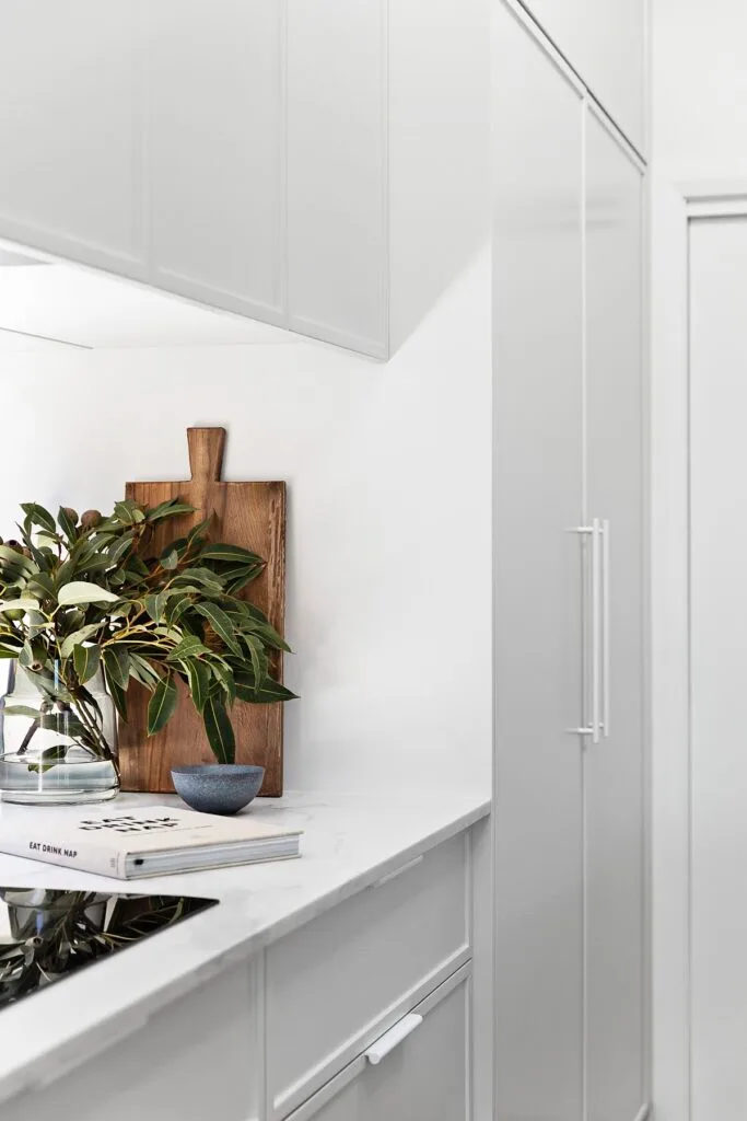 Minimalist white kitchen cupboards with white handles.