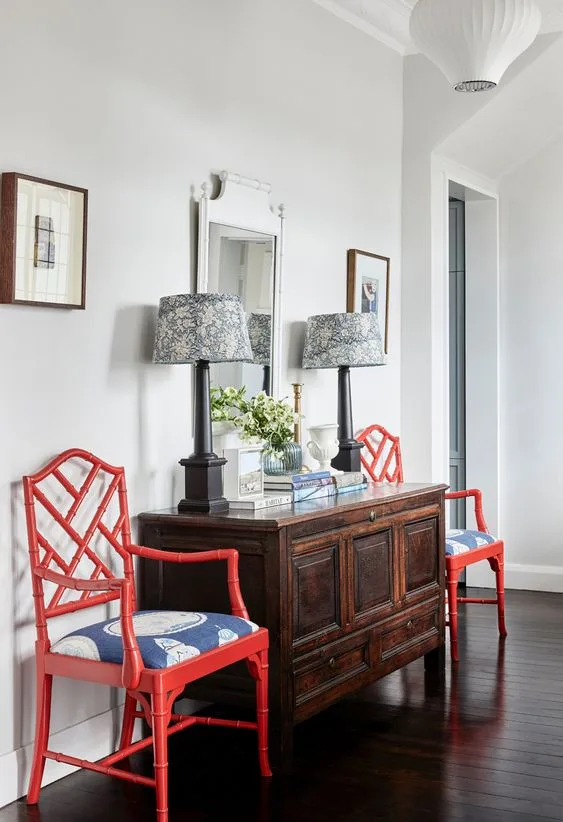 Entrance hall with red chairs next to secondhand sideboard.