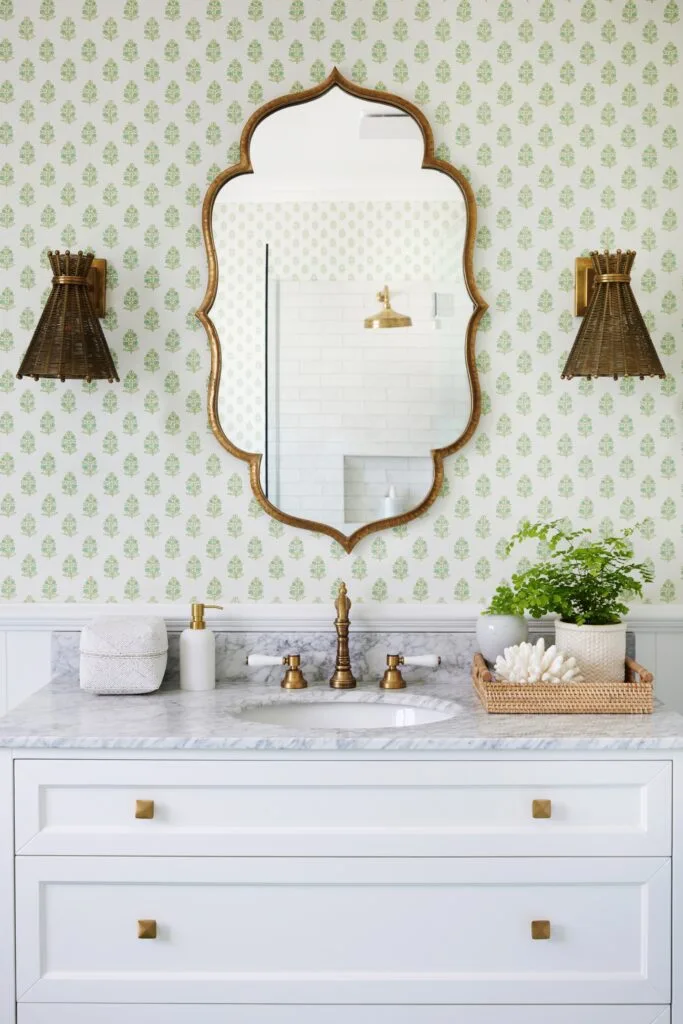 A modern country-style bathroom with green patterned wallpaper and a marble vanity.