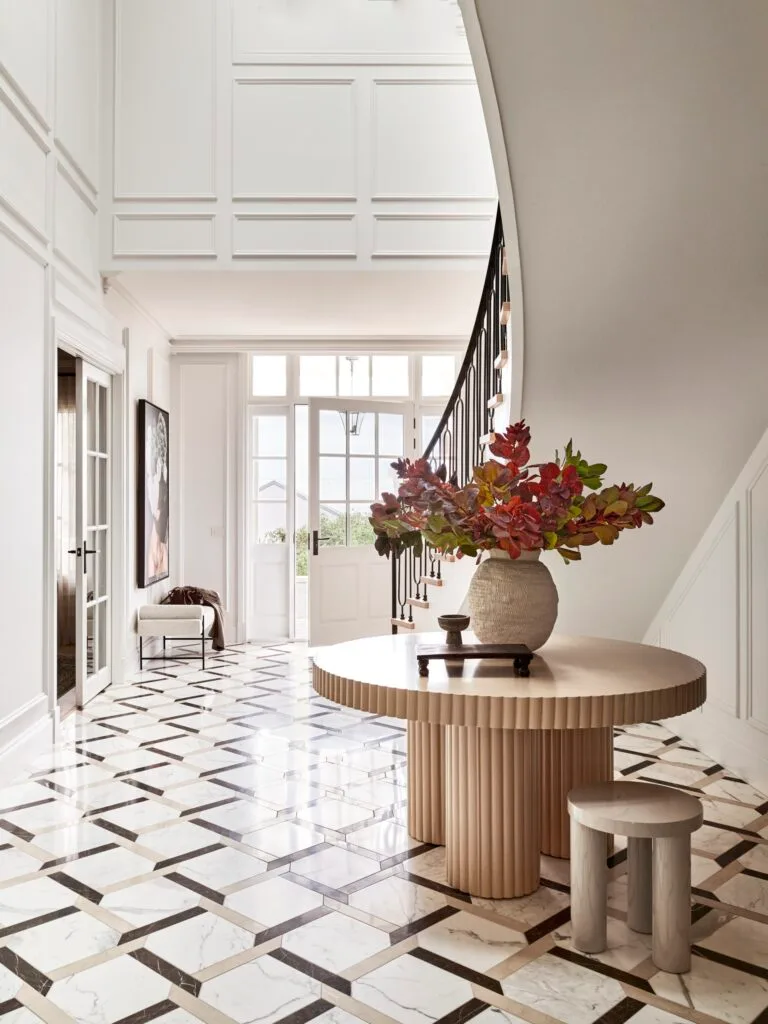 A large entry with a curved staircase and an Italian marble floor.