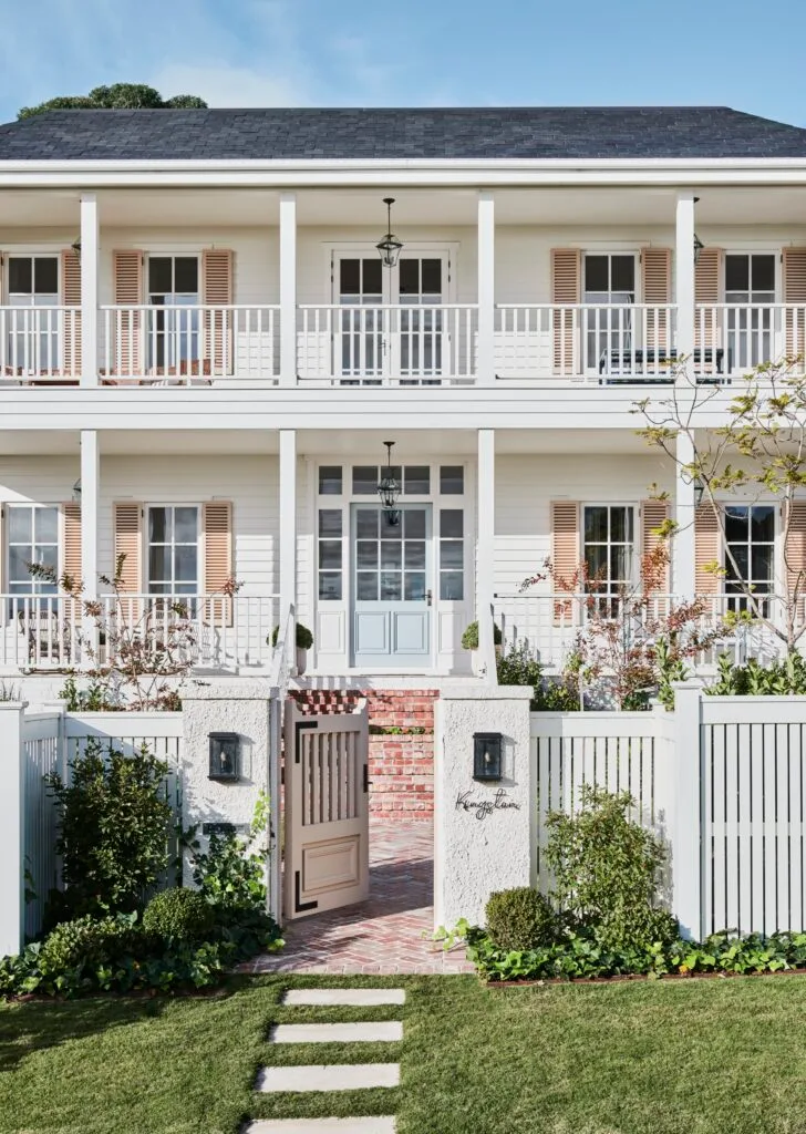 A classic two-storey manor style house with a white exterior and peach shutters.