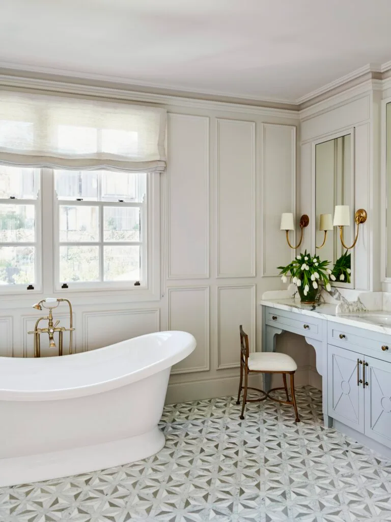 A white classic-style ensuite with a freestanding bath, mosaic tiles and wainscoting.