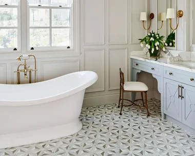 A white classic-style ensuite with a freestanding bath, mosaic tiles and wainscoting.