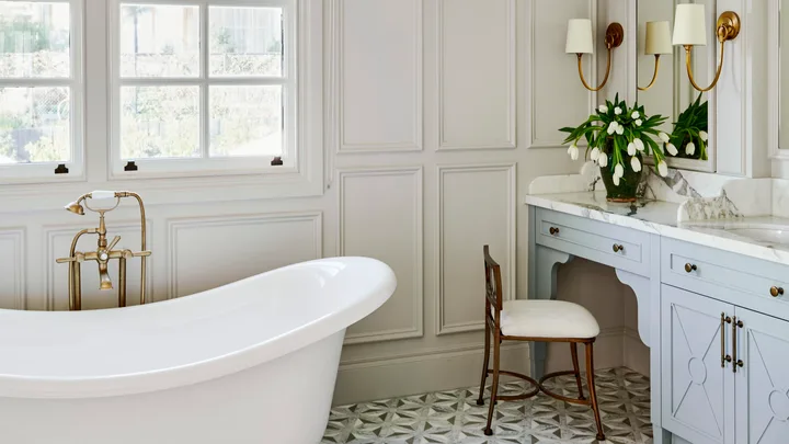 A white classic-style ensuite with a freestanding bath, mosaic tiles and wainscoting.