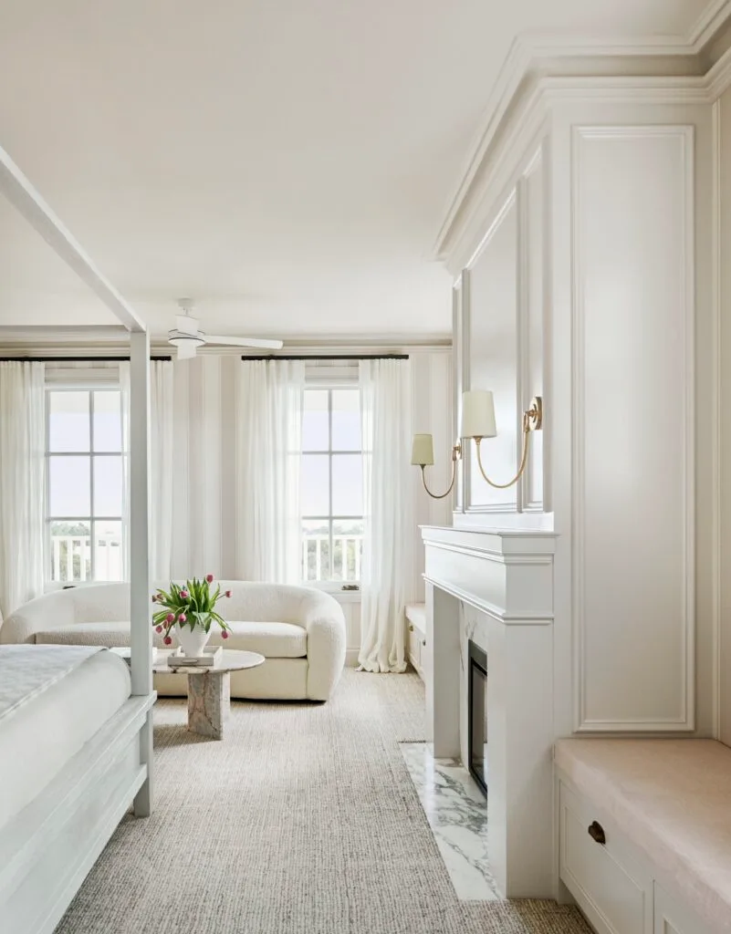 A classic white main bedroom suite with a marble fireplace.