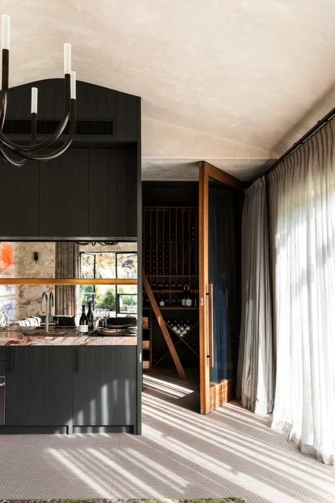 A home bar and wine cellar with chic black cabinetry and a kitchenette.