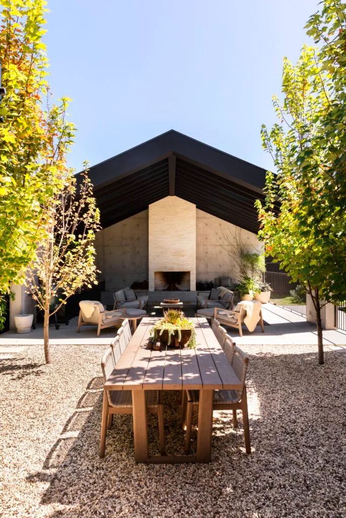 An outdoor seating area with an open brick fireplace.