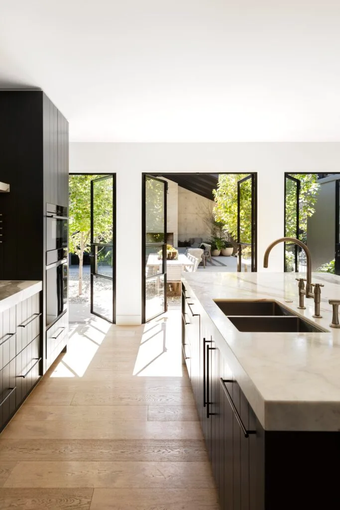 A modern indoor-outdoor kitchen in a black and white colour scheme.