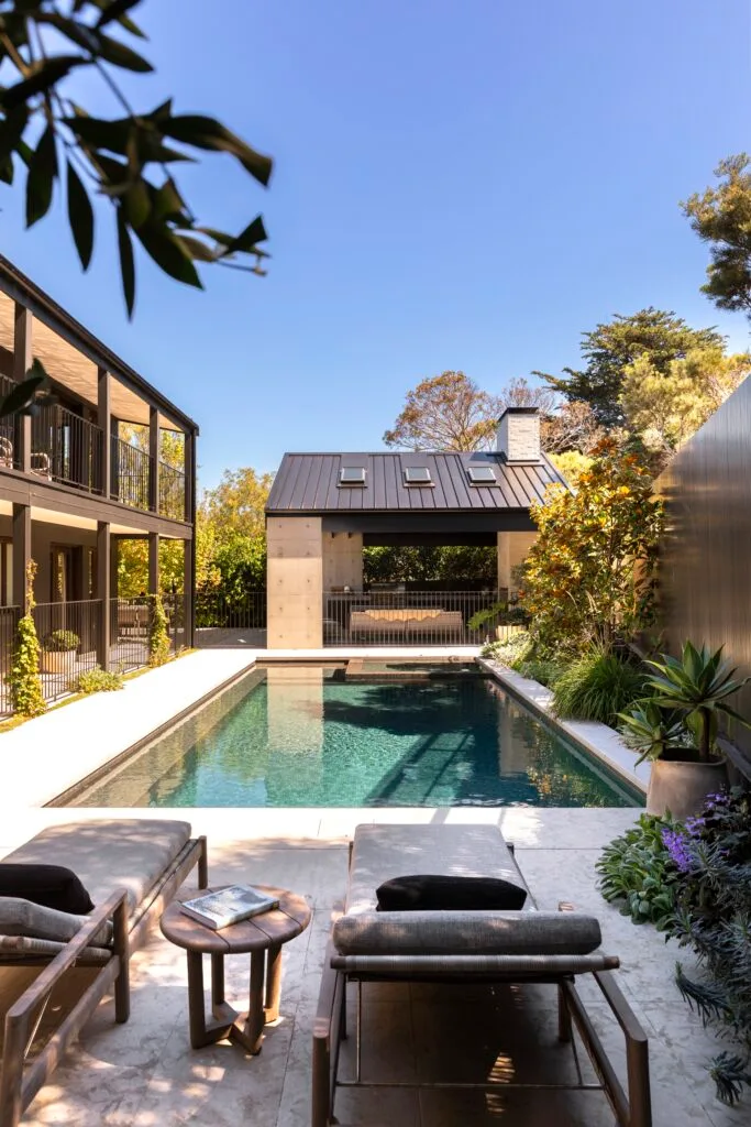 A mineral pool with loungers leading to a pavilion.