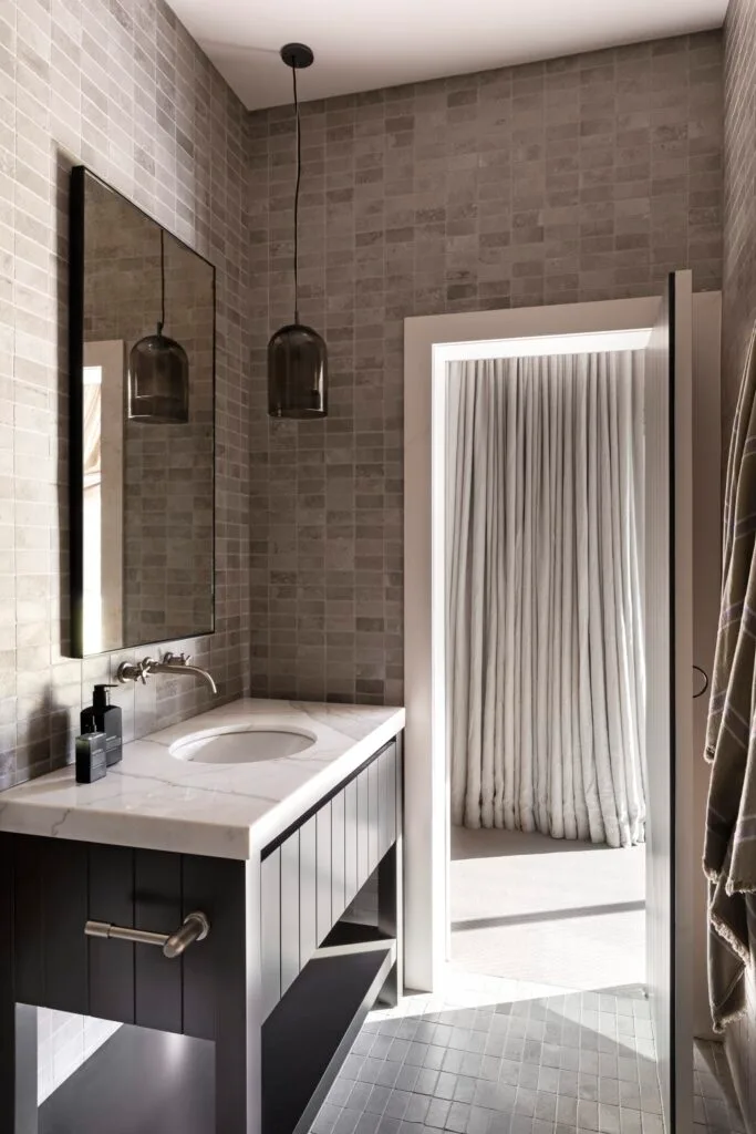 A shower room with a marble-topped vanity and stone walls.