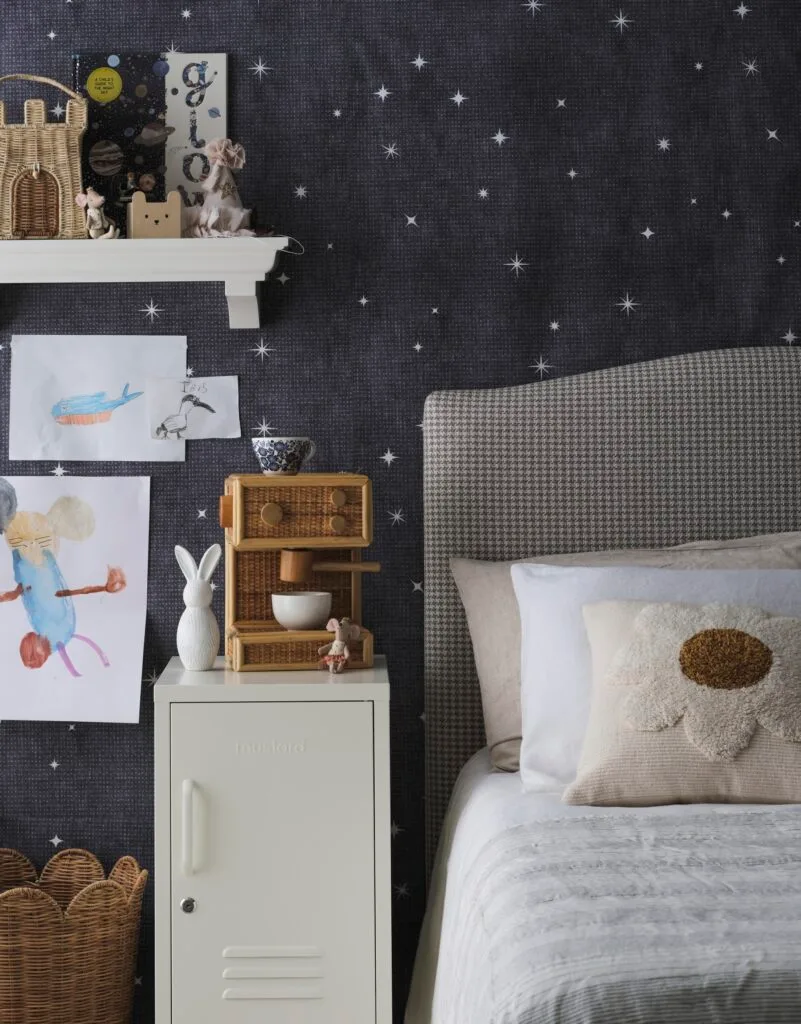 A kid's bedroom with star wallpaper and a blue checked bed.